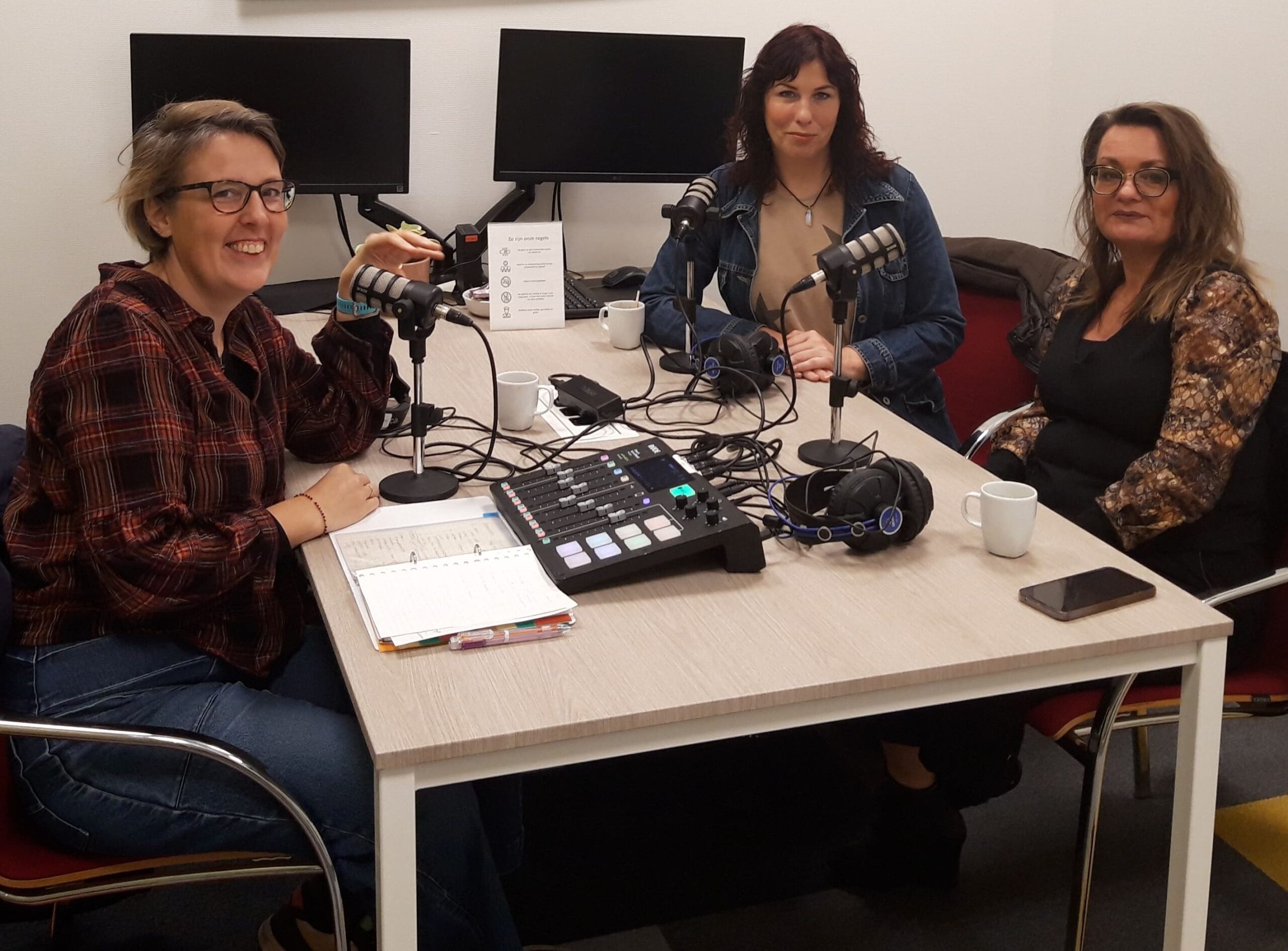 foto van drie mensen rond een podcastmicrofoon