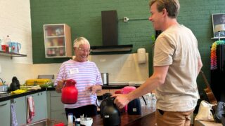 Vrijwilliger Gerrie met een koffiekan bij Gezellig
