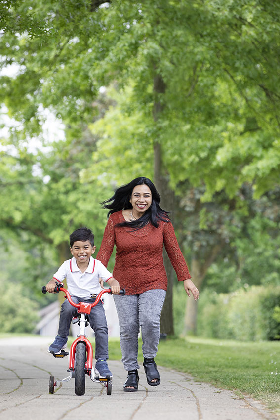 Foto van een vrouw die naast haar kleine dochter op een fietsje rent