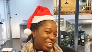 Medewerkers met kerstmuts die een hartjesgebaar maakt