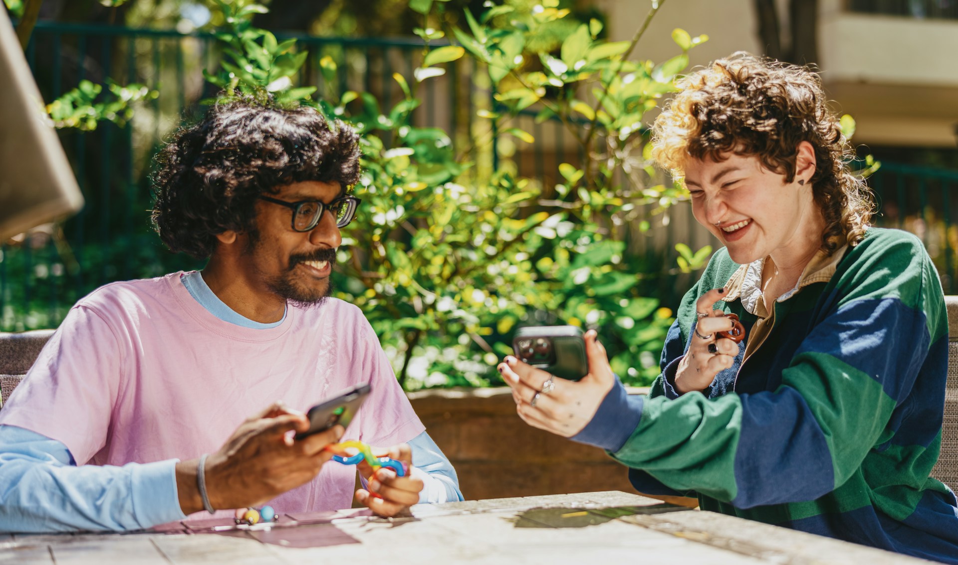 twee mensen aan een tafel. De ene laat diens telefoon zien aan de de andere persoon