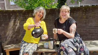 elena en dolly zitten op een picknicktafel. Elena schenk t iets te drinken in.